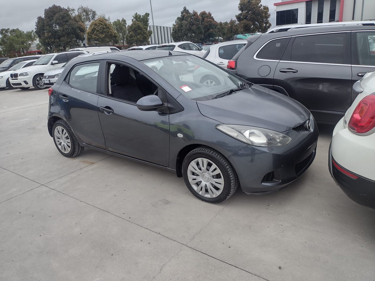 Grey hatchback parked beside other cars