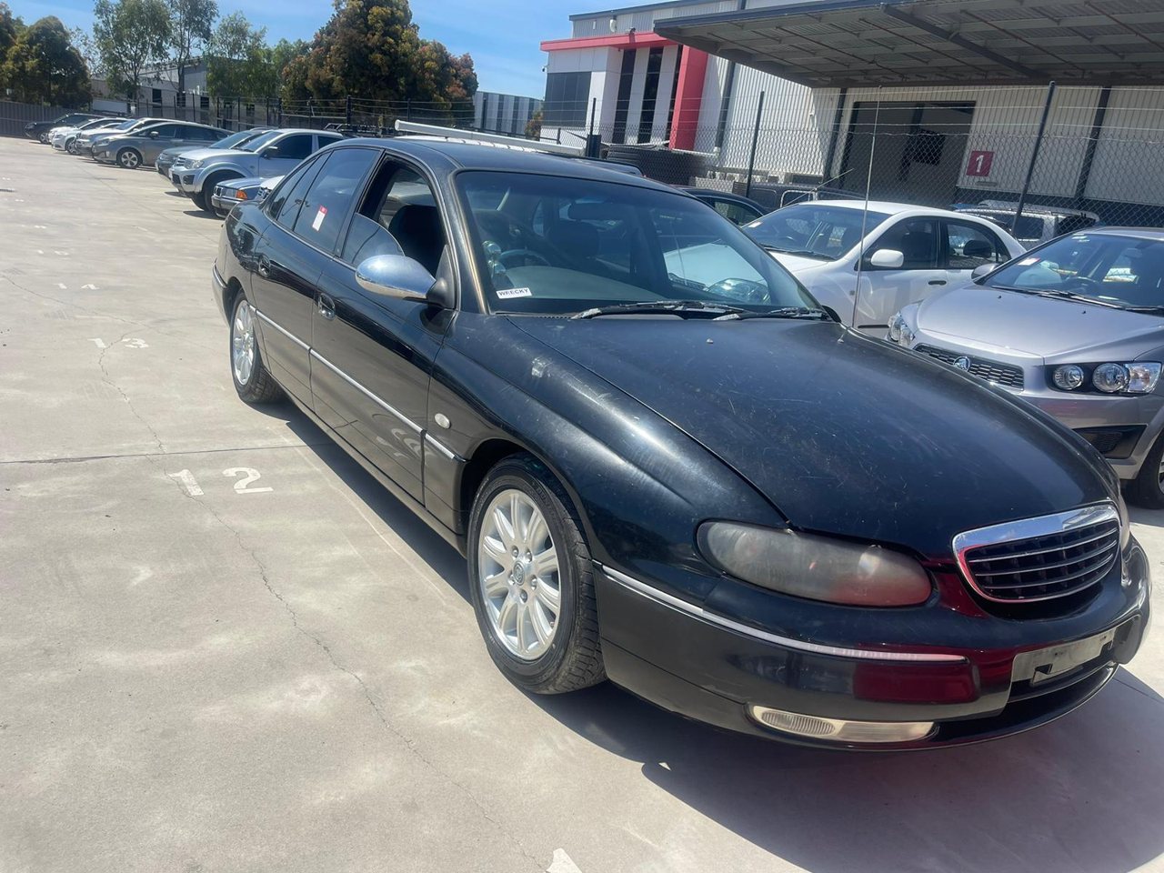 Dark sedan in a vehicle yard