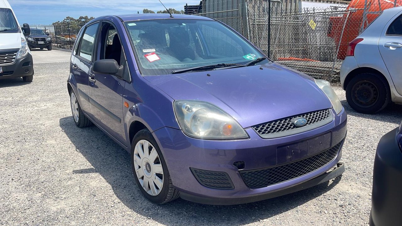 Blue compact hatchback in a vehicle yard