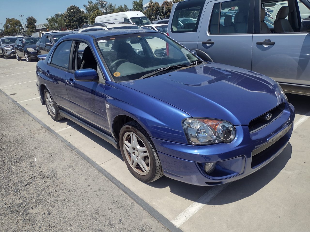 Blue sedan in an outdoor vehicle yard
